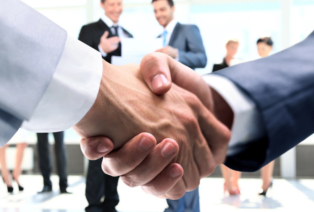 Two people shaking hands at a partnership meeting